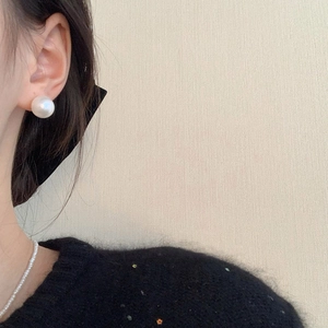 Close-up of elegant white pearl earrings and necklace worn by a woman for a chic look