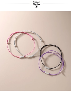Detailed view of woven bracelets in pink, grey, black and purple with silver beads