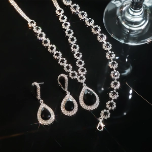 Detail view of water drop black gemstone necklace and earrings on reflective surface
