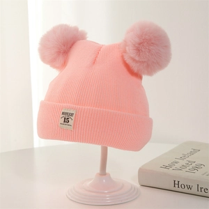 Pink knit baby beanie with double faux fur pom-poms and minimalist woven label