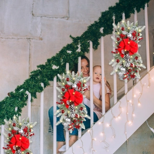 Christmas staircase garland with warm LED lights, red berries, cones and a big festive bow