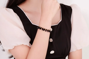 Detail of beaded bracelet with black teardrop beads and gold accents on wrist
