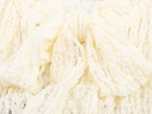 Close-up of intricate cream lace textures and decorative bow knot on the romper detail