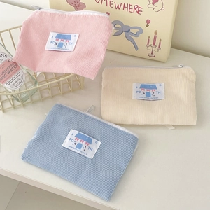 Dettaglio della trama in velluto a coste di pochette colorate con toppa fiocco carina