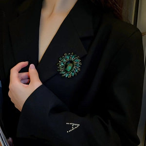 Close-up of vintage emerald flower brooch pinned on a black blazer lapel for women
