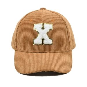 Nahaufnahme einer braunen Cord-Basecap mit einem weißen Chenille-Buchstaben-X-Patch