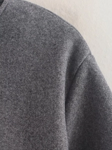 Gros plan sur la texture en laine grise et les coutures d'épaule du blouson bomber