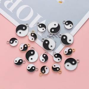 Macro detail of Yin Yang Tai Chi pendants in black and white drip oil alloy finish