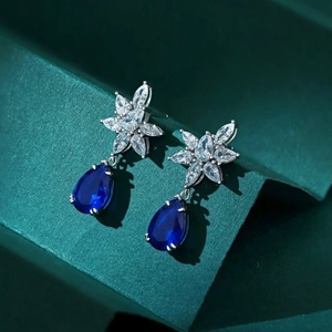 Macro detail of silver drop earrings featuring deep blue stones and floral zircon accents