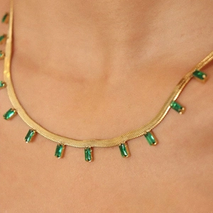 Flat gold snake chain necklace featuring green emerald cut zircon pendant drops
