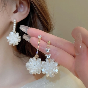 Dettaglio di orecchini a fiore con perle ed eleganti nappe di strass lucidi