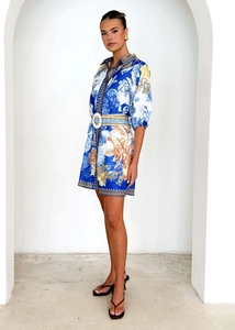 Dettaglio di un vestito a camicia con stampa barocca, cintura e motivo floreale blu