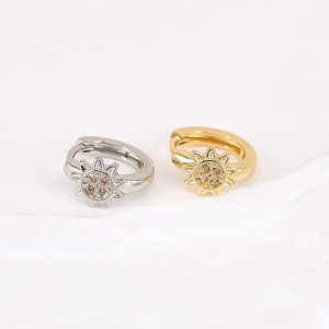 Detailed close-up of gold and silver sunburst huggie earrings with zircon crystals