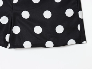 Close-up of black fabric with white polka dot patterns and high-quality hem stitching