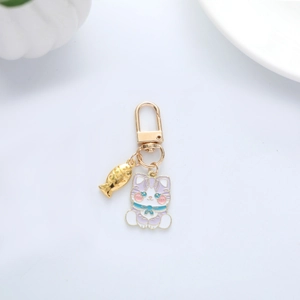 Close-up of a cartoon cat and fish metal keychain with purple enamel finish and gold hook