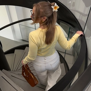 Vue arrière d'un mannequin en haut en tricot jaune et pantalon blanc sur un escalier en colimaçon