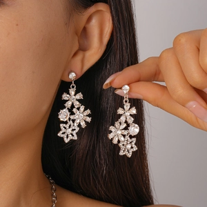 Close-up of silver floral earrings with sparkling rhinestones worn by a model