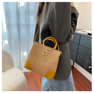 Brown faux suede bucket bag with embossed monogram pattern shown on a model