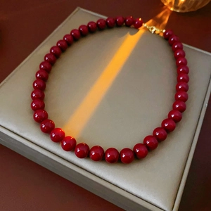 Detail of red beaded stainless steel necklace with gold clasp on jewelry box