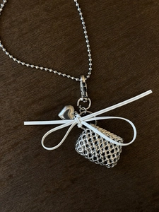 Detail of silver woven bag pendant with heart charm and white leather bow on bead chain