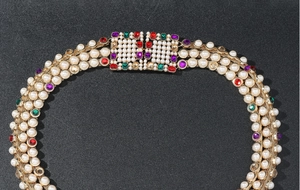 Close-up of ornate metal waist chain with colorful rhinestones and layered pearls