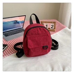 Détail du sac à dos en velours côtelé bordeaux avec bretelles sur un bureau décontracté
