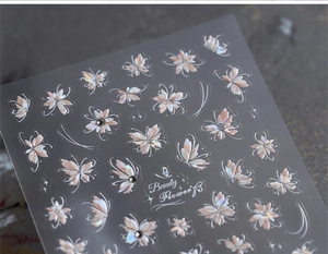 Detailed macro view of laser holographic butterfly and flower nail stickers with rhinestones
