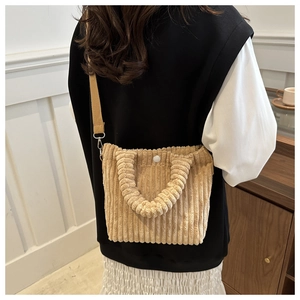 Detail of light brown corduroy tote bag showing vertical texture and crossbody strap
