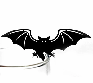 Detail of a black bat-shaped place card decoration clipped onto a glass for Halloween parties