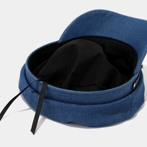 Detail view of the denim military cap interior with black lining and adjustable strap