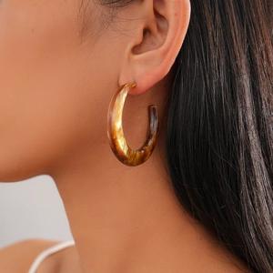 Detail of vintage resin C-shape hoop earrings with amber tortoiseshell texture on model
