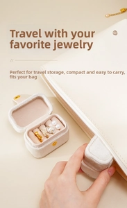 Mini travel jewelry box showing ring slots and earrings being placed in a bag