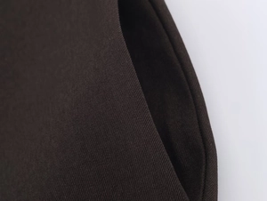 Macro shot of dark brown twill fabric texture and pocket structure on a modern blazer