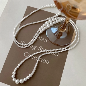 Long multi-strand pearl necklace with geometric layering and smooth white finish