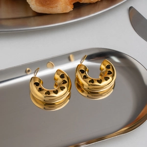 Macro view of vintage hollow heart C-shaped hoop earrings with 18K gold plated finish.