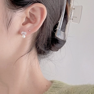 Detail shot of a square-cut zirconia and white pearl stud earring on model