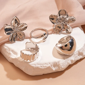 Five-piece silver flower and geometric open ring set on elegant silk background