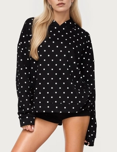 Close-up of black hoodie with white polka dots featuring front pocket and ribbed cuffs