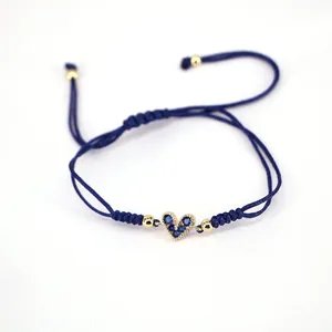 Detail of blue braided adjustable bracelet with gold heart charm and blue zircon inlay