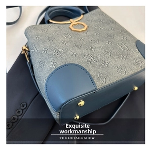 Detail of blue jacquard fabric bucket bag with gold lock and leather base corners