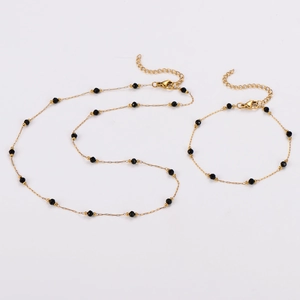 Vue détaillée de l'ensemble collier et bracelet en acier doré avec perles noires