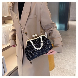 Detail of vintage black velvet shell bag featuring pearl handle and gold chain strap
