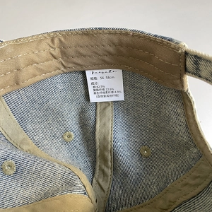 Detail view of denim cap inner tag showing 82.5% cotton material and 56-58cm size