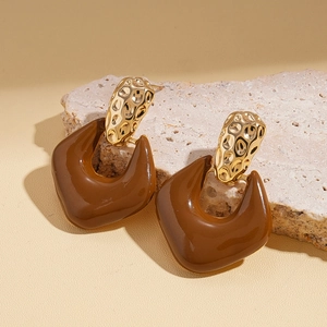 Detail of vintage geometric earrings with hammered gold texture and brown resin pendant