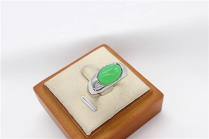 Macro detail of oval green gemstone set in a thick polished silver stainless steel band