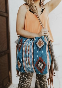 Detail of bohemian knit tote bag featuring geometric patterns and long leather tassels