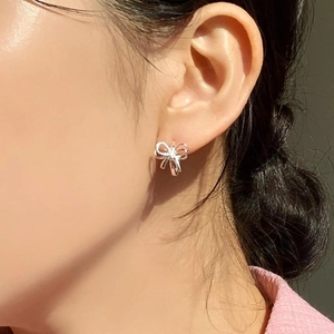 Minimalist 925 sterling silver butterfly stud earrings worn by model in natural sunlight