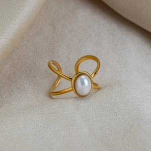 Detailed close-up of a gold 18K plated oval pearl ring on elegant champagne silk fabric