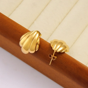 Macro shot of 18K gold plated stainless steel scallop shell stud earrings on wooden tray