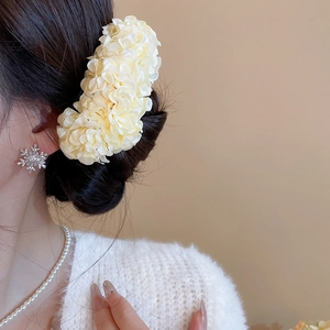 Detail of yellow fabric flower hair pin styled on an elegant side bun hairstyle